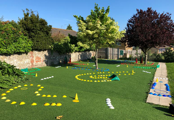 A colorful outdoor area featuring bright cones and markers arranged on artificial grass, designed for children's golf activities and play.